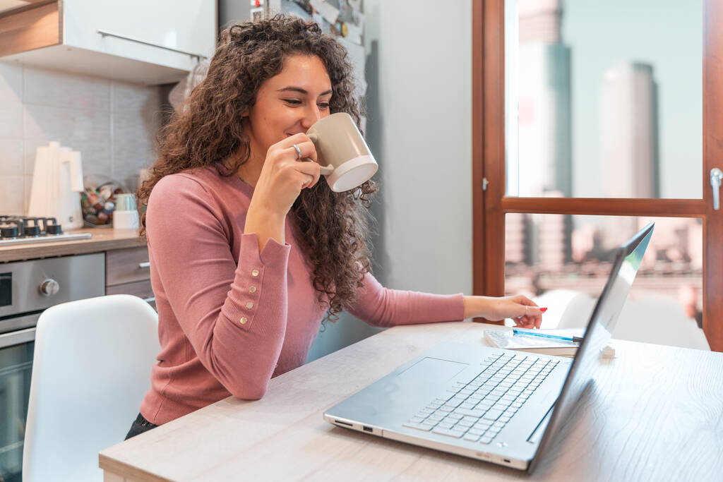 Genç kadın, covid-19 salgını nedeniyle kısıtlamalar sırasında evde bilgisayar başında çalışıyor. Bulaşıcı hastalıkları önleme kavramı - Fotoğraf, Görsel