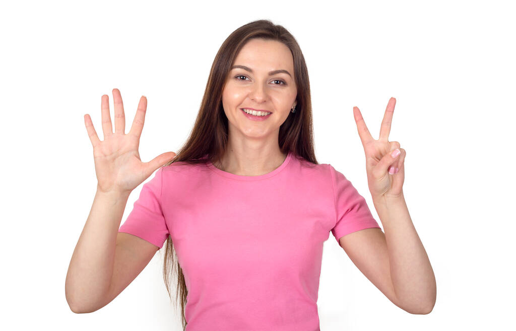 Pembe kazaklı genç kadın, beyaz arka planda 7 parmak gösteriyor.. - Fotoğraf, Görsel