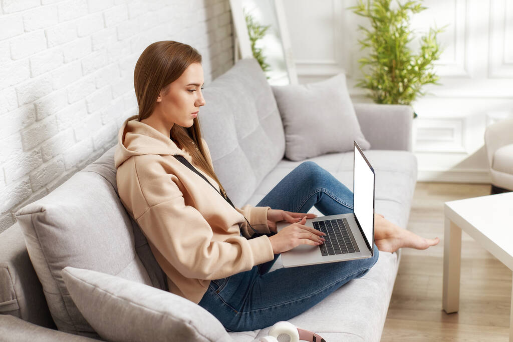Nuori nainen käyttää kannettavaa tietokonetta kotona - Valokuva, kuva