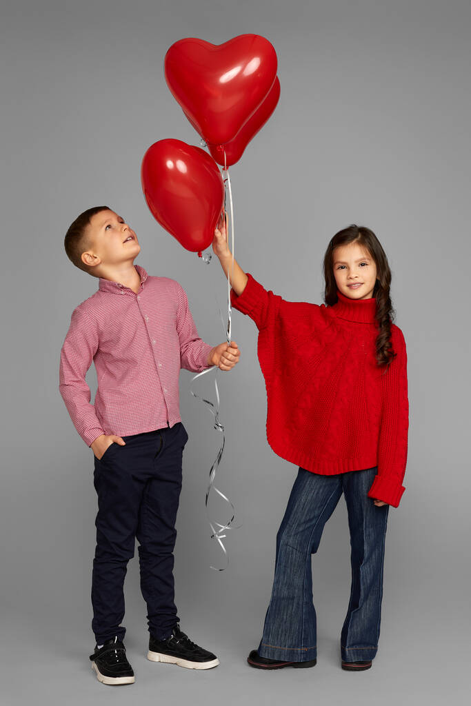 coppia di bambina e ragazzo con palloncini cuore rosso - Foto, immagini