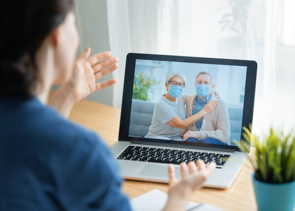Senior couple wearing face masks and using pc for remote talking during coronavirus and flu outbreak. Virus and illness protection, home quarantine. COVID-2019. - Photo, Image