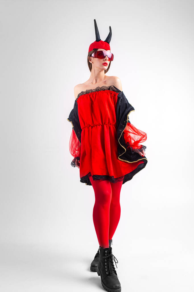 Sexy devil girl in red tights and black boots posing on white studio background. - Photo, Image