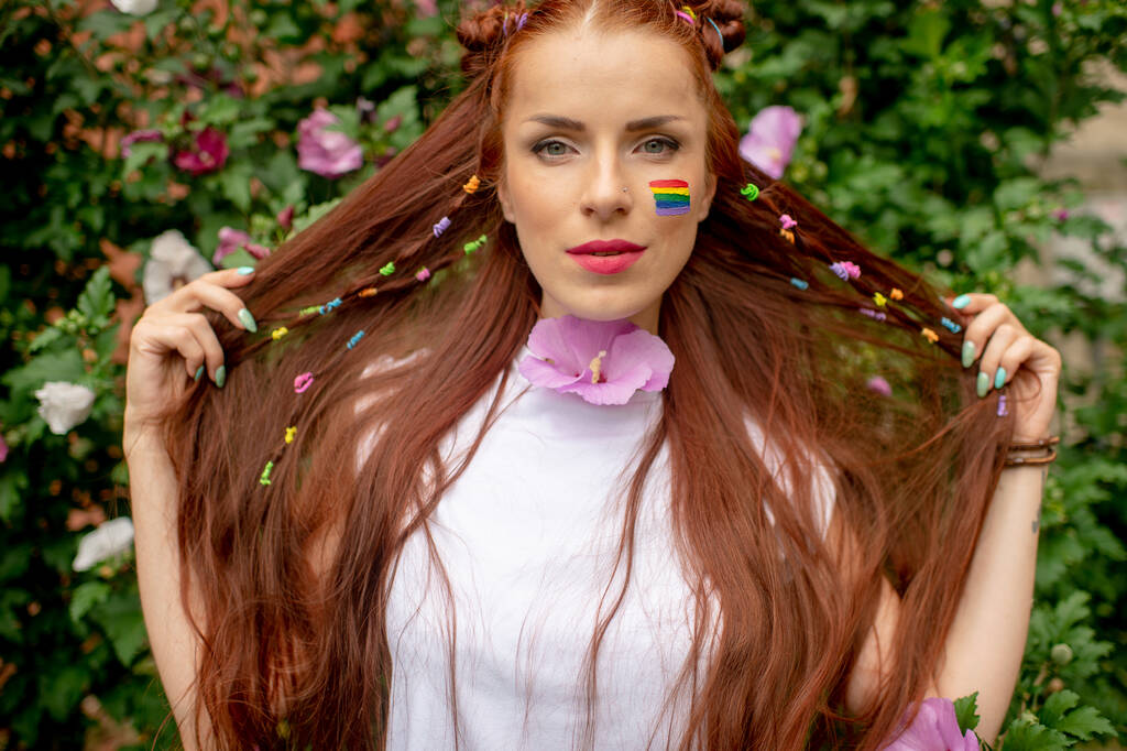 Allegro lesbica con lgbt arcobaleno sul suo viso in posa in fiore fiori - Foto, immagini