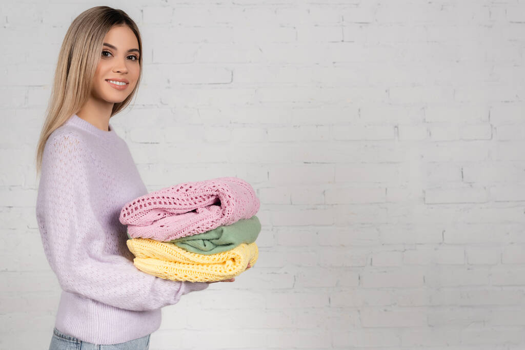 Junge Frau mit bunt gestrickten Pullovern blickt in die Kamera auf weißem Hintergrund - Foto, Bild