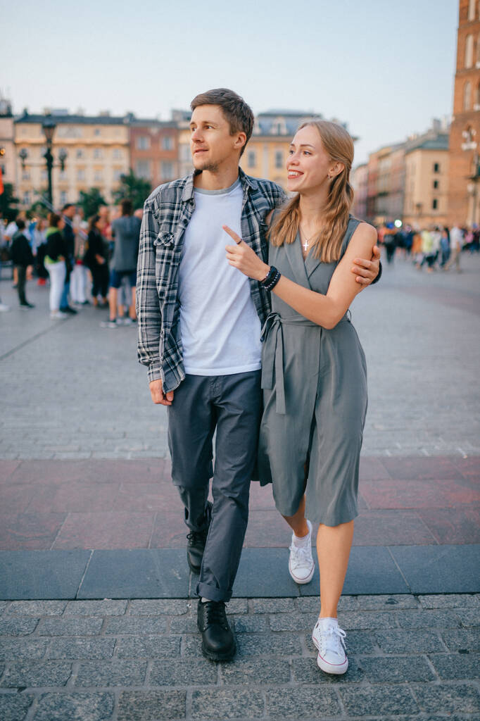 Onnellinen rakastava pari hymyilee ja kävelee Krakovan pääaukiolla (Krakova) - Valokuva, kuva