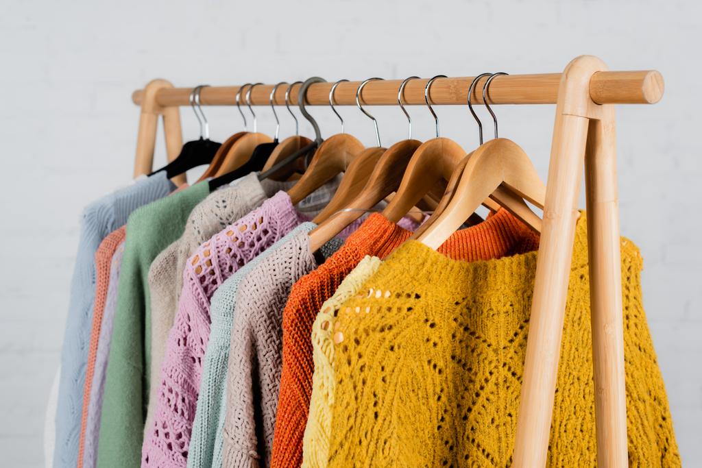 Hangers with colorful sweaters on hanger rack on white background  - Photo, Image