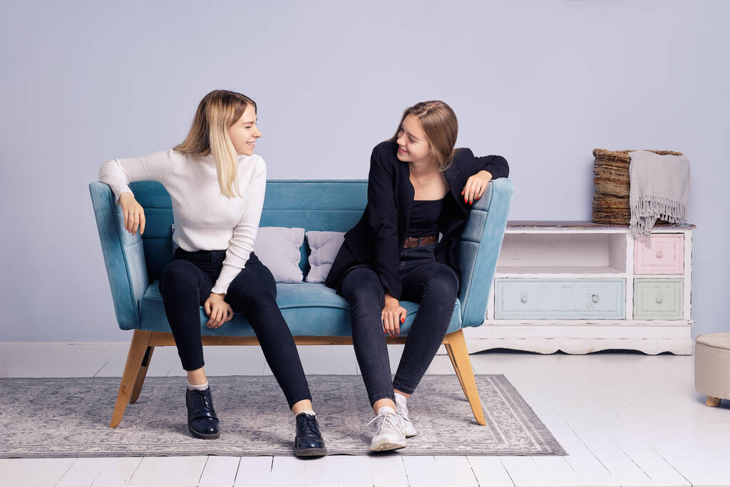 Dos chicas hablando juntas en el sofá. Amistad y relaciones adolescentes. - Foto, Imagen