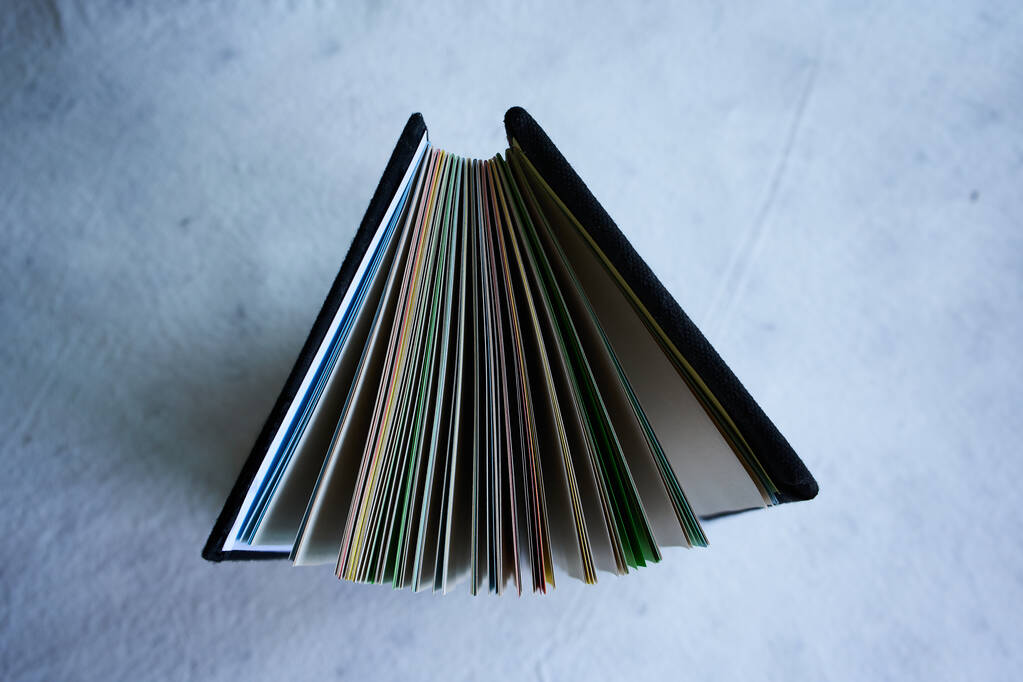 Μια κορυφαία άποψη ενός χαρτοφυλακίου φακέλων με πολύχρωμα φύλλα χαρτιού που απομονώνονται σε λευκό φόντο - Φωτογραφία, εικόνα