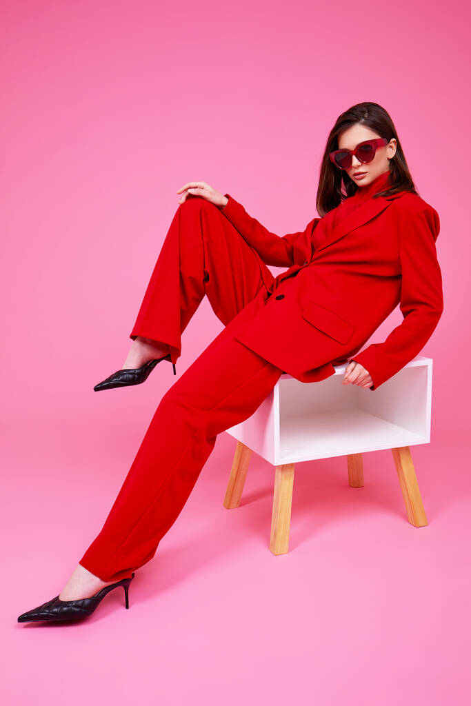 Модна модель в червоному костюмі та сонцезахисних окулярах. Студійний знімок
. - Фото, зображення