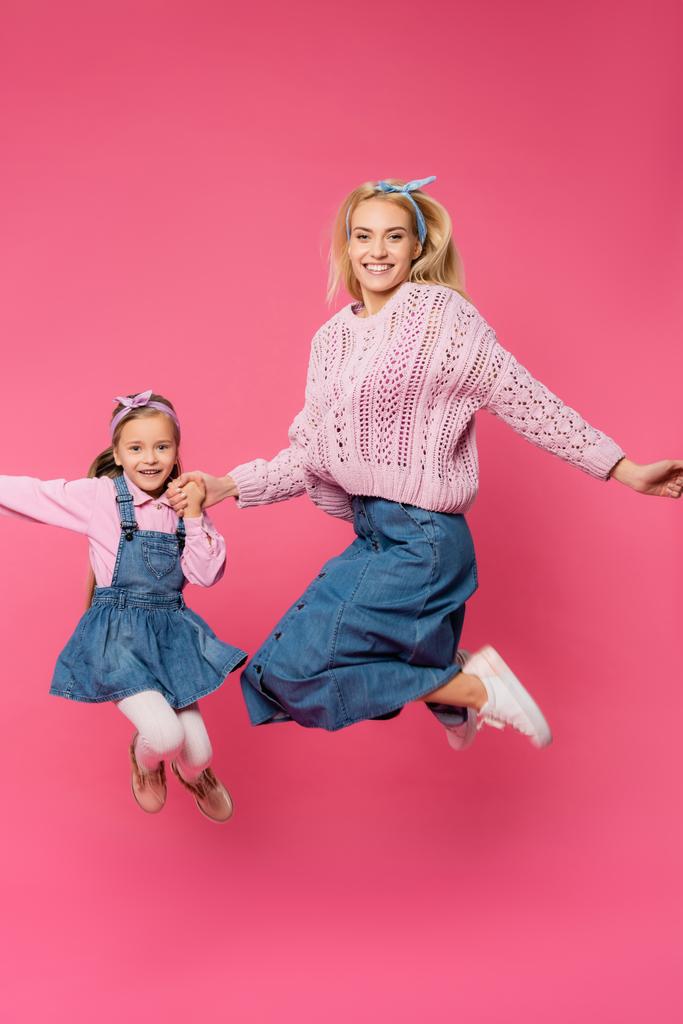 Mutter und Kind lächeln und springen auf rosa - Foto, Bild