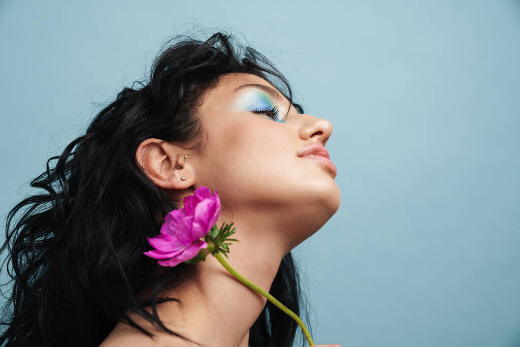 Primo piano di una bella giovane donna sensuale che indossa trucco posa isolata su sfondo blu - Foto, immagini
