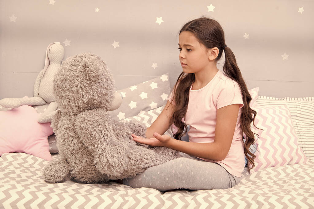 Kommunikation. Lieblingsspielzeug. Mädchen Kind umarmen Teddybär in ihrem Schlafzimmer. Angenehme Zeit im gemütlichen Schlafzimmer. Mädchen Kind lange Haare süße Pyjamas entspannen und spielen Plüsch-Teddybär-Spielzeug. Fantasievolle Interaktion - Foto, Bild