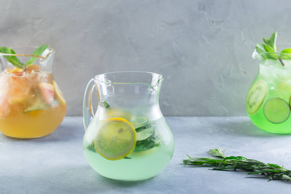  Limonada de cor diferente em decantadores de vidro com frutas e hortelã fresca - Foto, Imagem