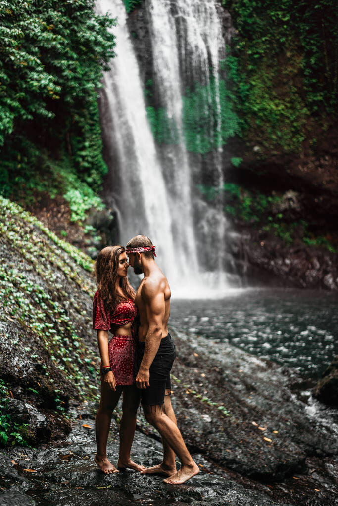 Egy szerelmespár egy vízesésen. Nászút. Boldog pár Bali szigetén. A gyönyörű pár beutazza a világot. Utazás Indonéziába. Boldog pár nyaralni. Esküvői kirándulás. Fénymásolási hely - Fotó, kép