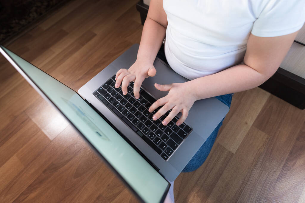 Kleines Mädchen sitzt auf dem Fußboden und ist mit Laptop beschäftigt - Foto, Bild