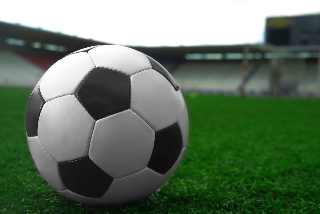 bílý a černý fotbalový míč na zelené trávě a na pozadí stadionu. sportovní sázení nápad - Fotografie, Obrázek