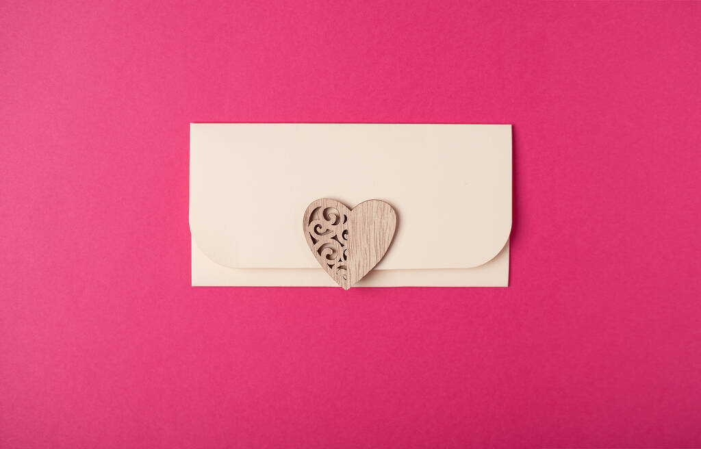 Envelope and wooden heart on the hot pink background. Flat lay. Romantic love letter for Valentine's day concept. - Photo, Image