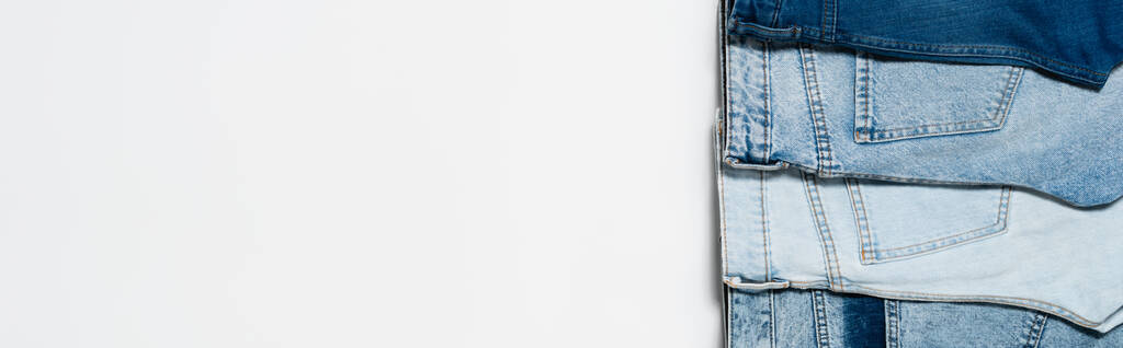 verticale rij van verschillende blauwe jeans op witte achtergrond, bovenaanzicht, banner - Foto, afbeelding