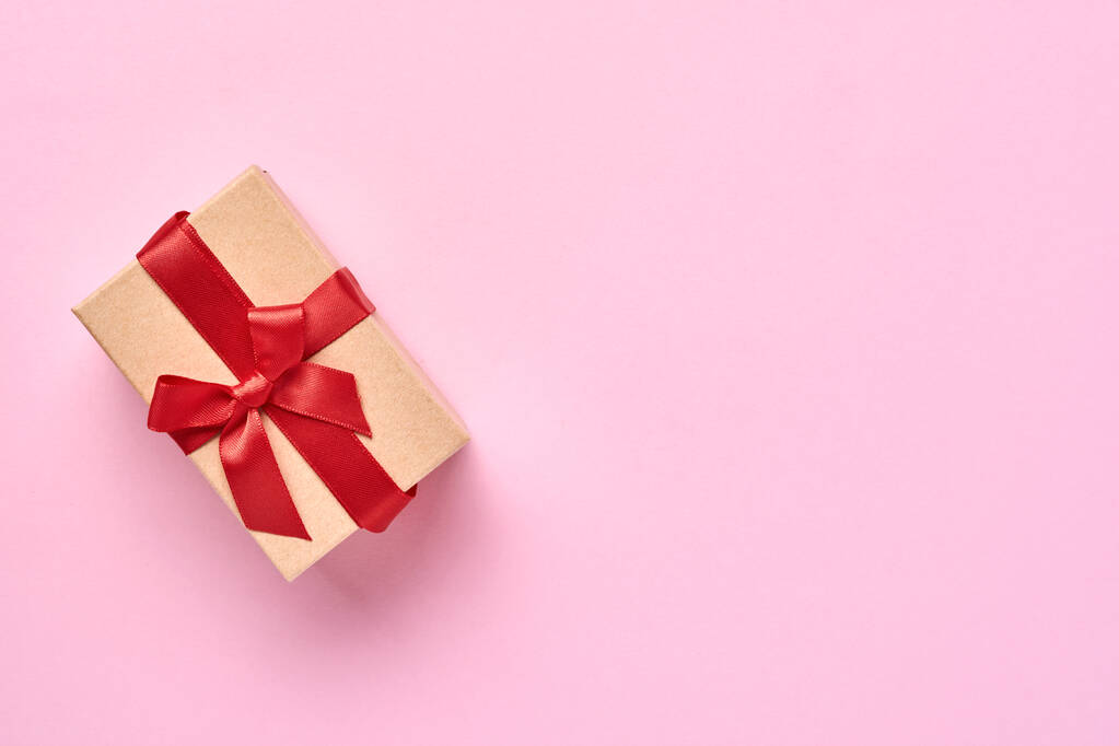 Όμορφο κουτί δώρου με κόκκινη κορδέλα σε ένα ροζ φόντο τοίχο. Ευχετήρια κάρτα Αγίου Βαλεντίνου. Άνω όψη. - Φωτογραφία, εικόνα