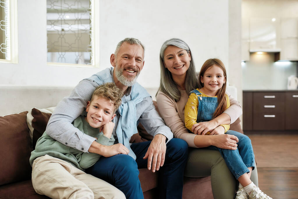 Portret szczęśliwej rodziny spędzającej czas w domu, dziadkowie i wnuki relaksujące się na kanapie w salonie, uśmiechnięte do kamery - Zdjęcie, obraz