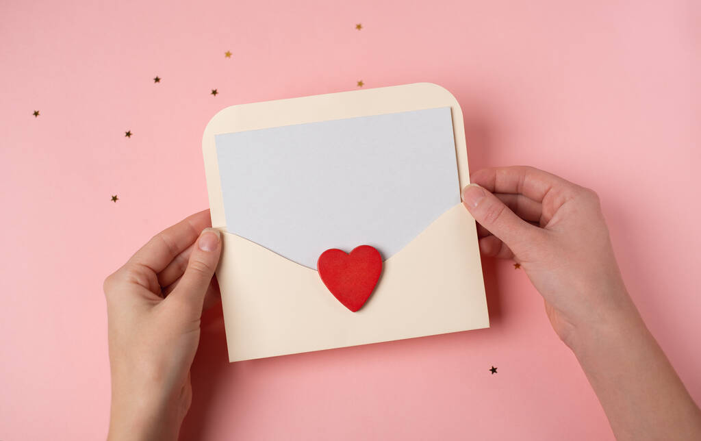 Frauenhände mit einem Brief im Umschlag auf rosa Hintergrund. Valentinstag-Konzept. Raum für Text. - Foto, Bild