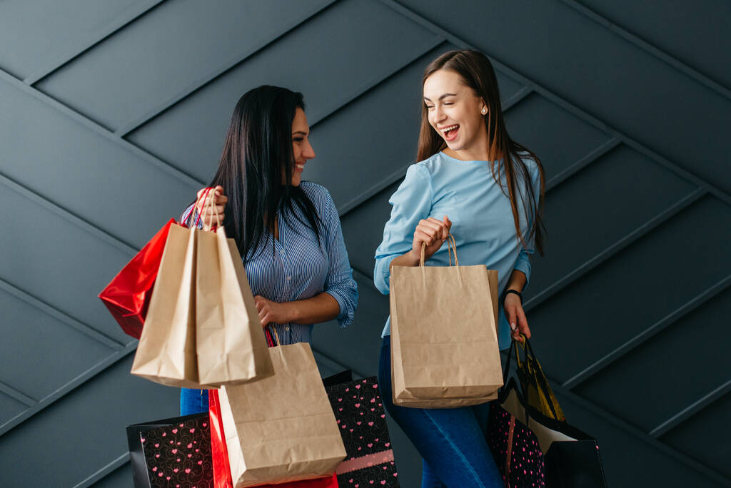 Две счастливые девушки радуются своим покупкам, черная пятница концепции - Фото, изображение