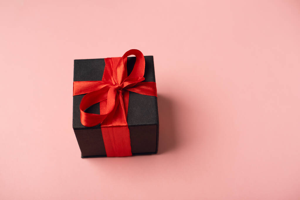 Cajas de regalo negras con cinta roja sobre fondo rosa. El concepto del Día de San Valentín. - Foto, imagen
