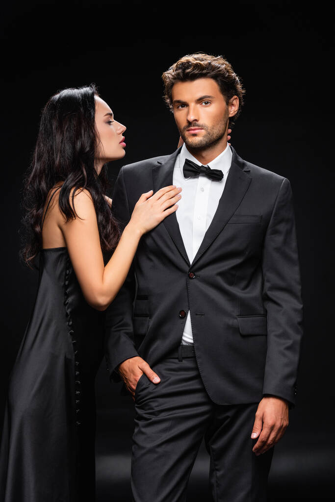 seductive brunette woman seducing elegant confident man isolated on black - Photo, Image