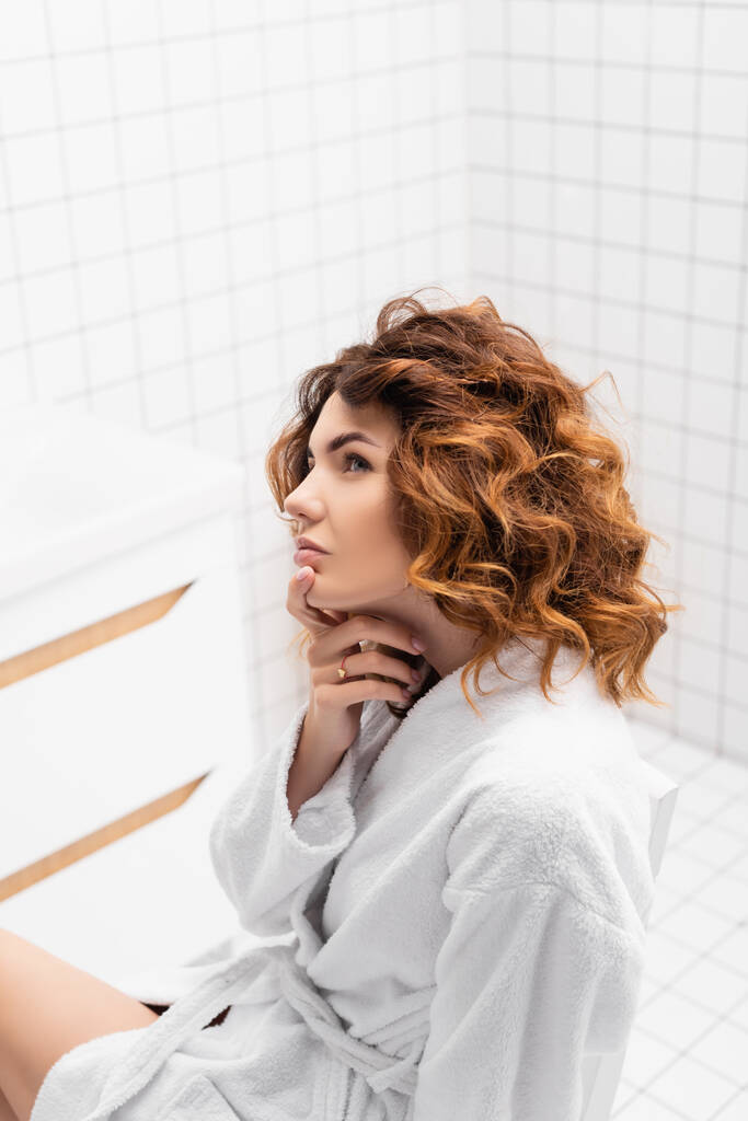 Pensive kobieta w białym szlafroku patrząc daleko w łazience  - Zdjęcie, obraz