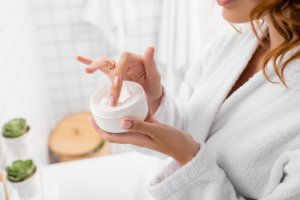 Gewassen uitzicht van de vrouw met cosmetische crème in de badkamer  - Foto, afbeelding