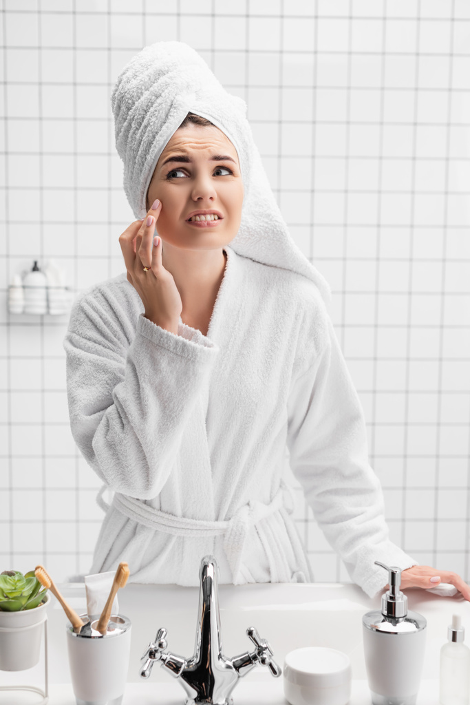 Mulher descontente em toalha tocando bochecha no banheiro  - Foto, Imagem