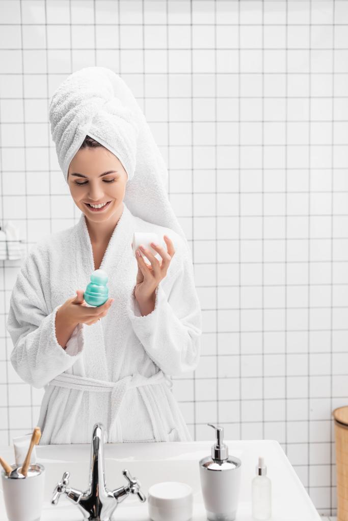 Mulher alegre em toalha e roupão de banho segurando desodorizante no banheiro moderno  - Foto, Imagem