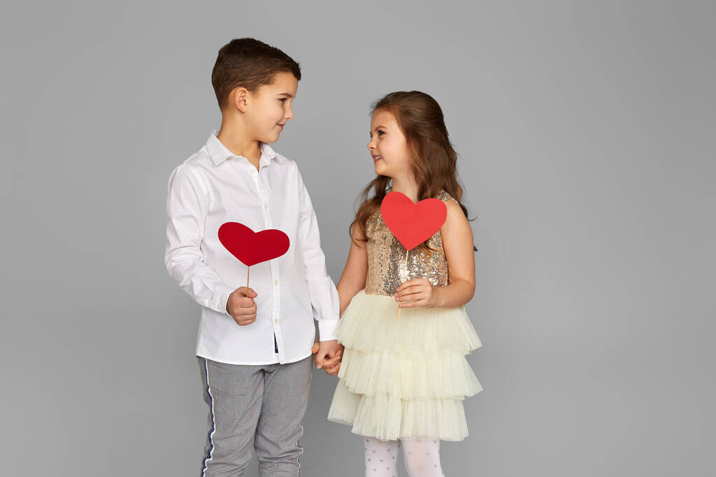 Счастливая пара маленькая девочка и мальчик с красными сердцами - Фото, изображение