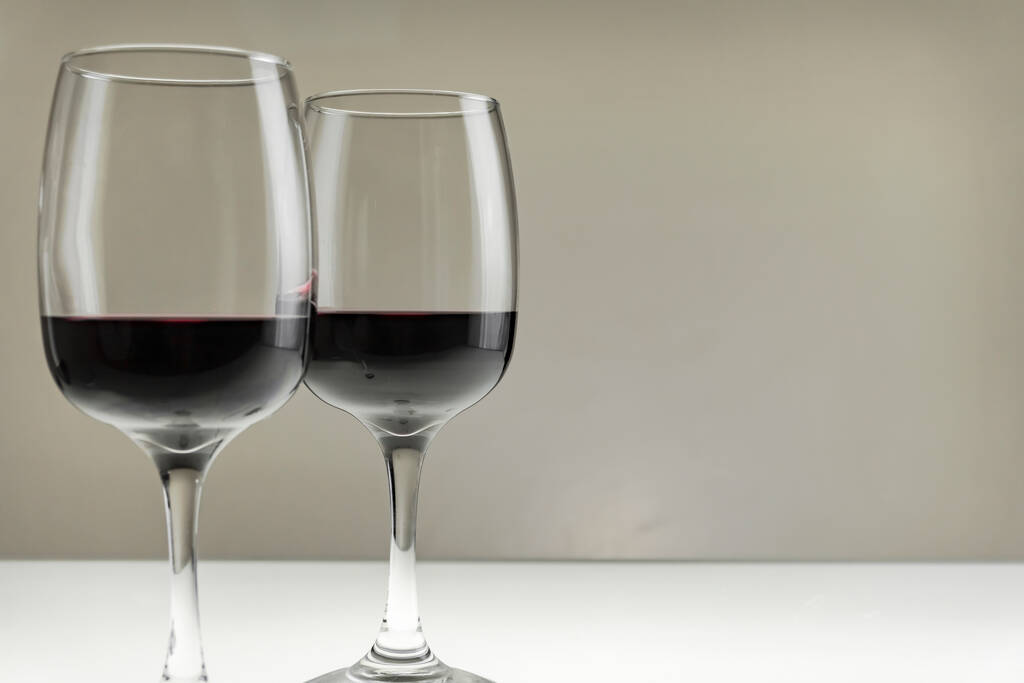 Zwei große Gläser mit Rotwein auf verschwommenem Hintergrund, Nahaufnahme. - Foto, Bild