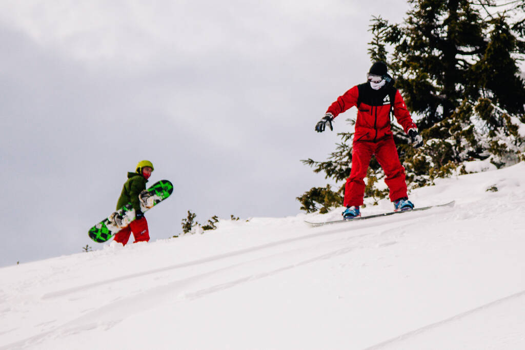Guy in bright red jumpsuit rides freeride on a snowboard - Photo, Image