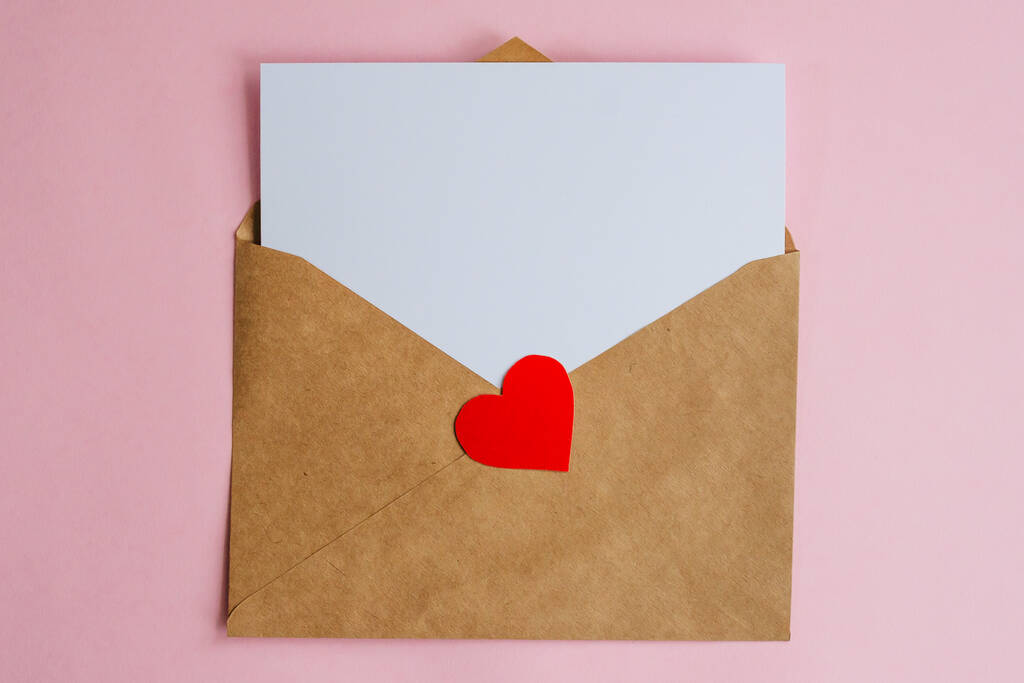 Kraft koperta z białym arkuszem papieru i czerwone serce na różowym tle. Leżał płasko z przestrzenią kopiującą. Koncepcja Walentynek - Zdjęcie, obraz