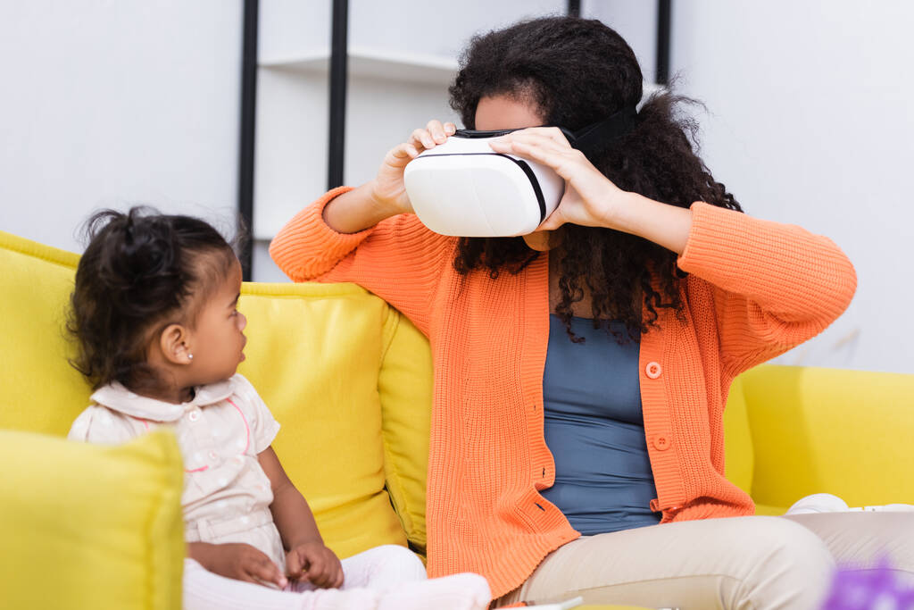 Afrika kökenli Afrikalı Amerikalı çocuk VR kulaklıklı anneye bakıyor.  - Fotoğraf, Görsel