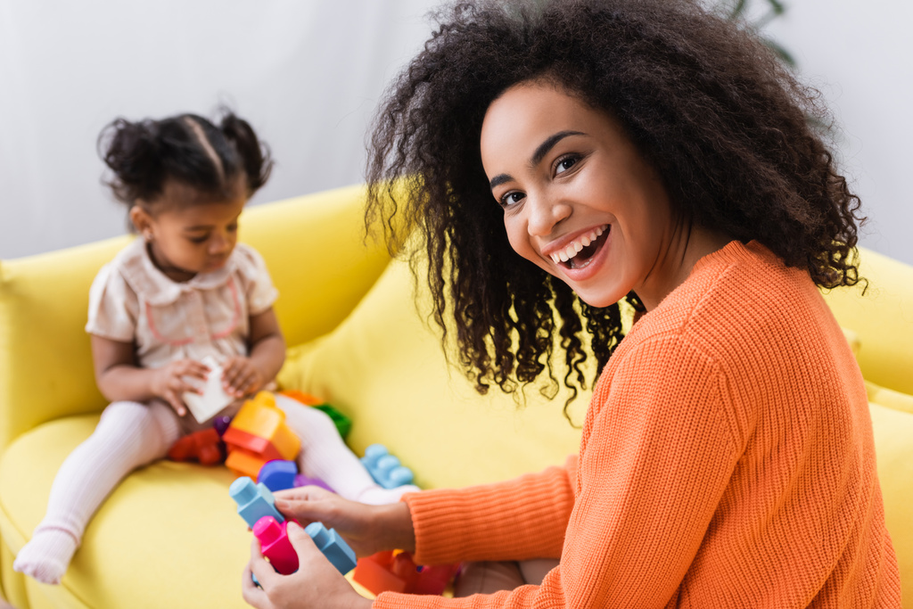 boldog afro-amerikai anya játszik építőkockák kisgyerek homályos háttér - Fotó, kép