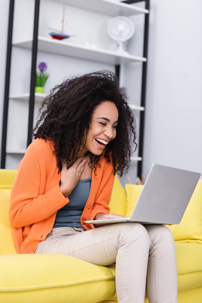 happy african american freelancer laughing while using laptop at home - Photo, Image