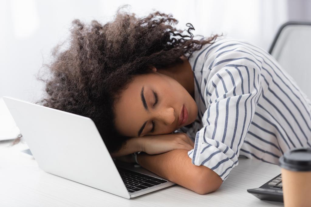 εξαντλημένη Αφροαμερικανή που κοιμάται στο λάπτοπ στο σπίτι. - Φωτογραφία, εικόνα