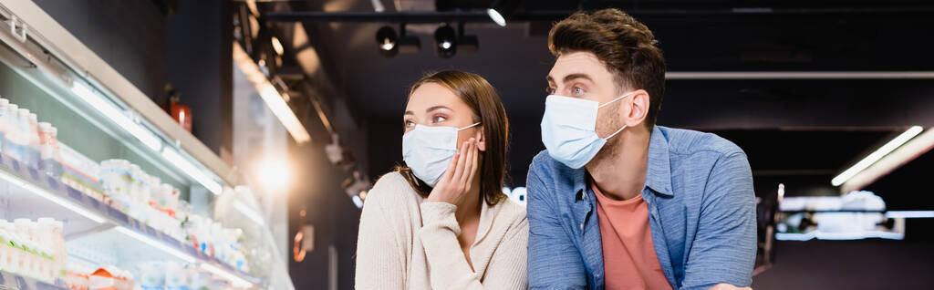 Young couple in medical masks in supermarket, banner  - Foto, imagen