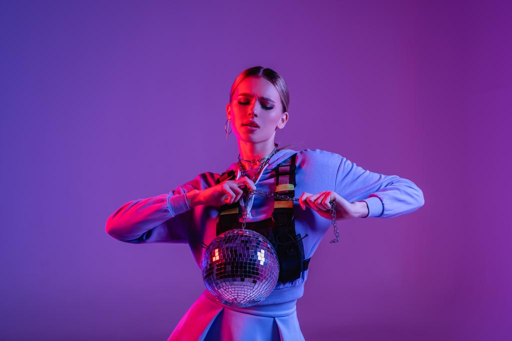 giovane ed elegante donna in posa con lucida palla da discoteca viola - Foto, immagini