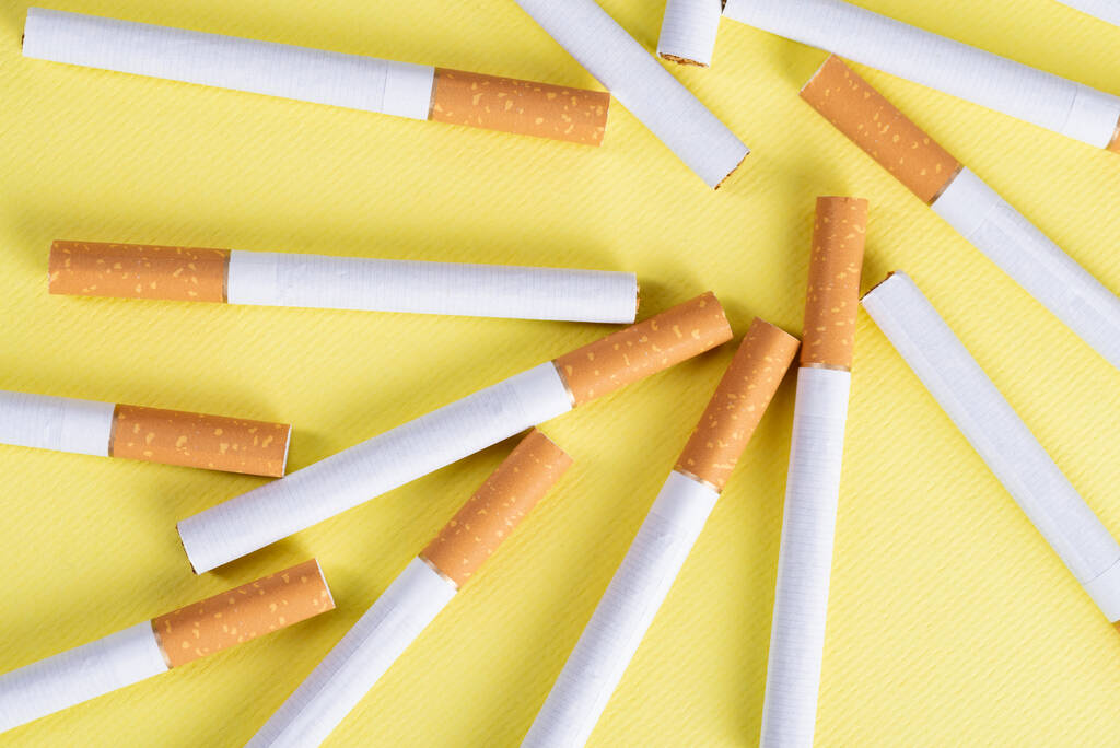 Sarı arka planda bir sürü endüstriyel sigara var.. - Fotoğraf, Görsel