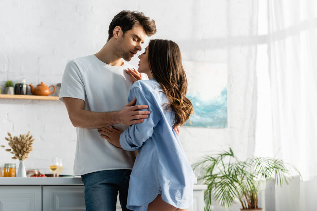 man hugging sensual woman in blue shirt in kitchen  - Photo, Image