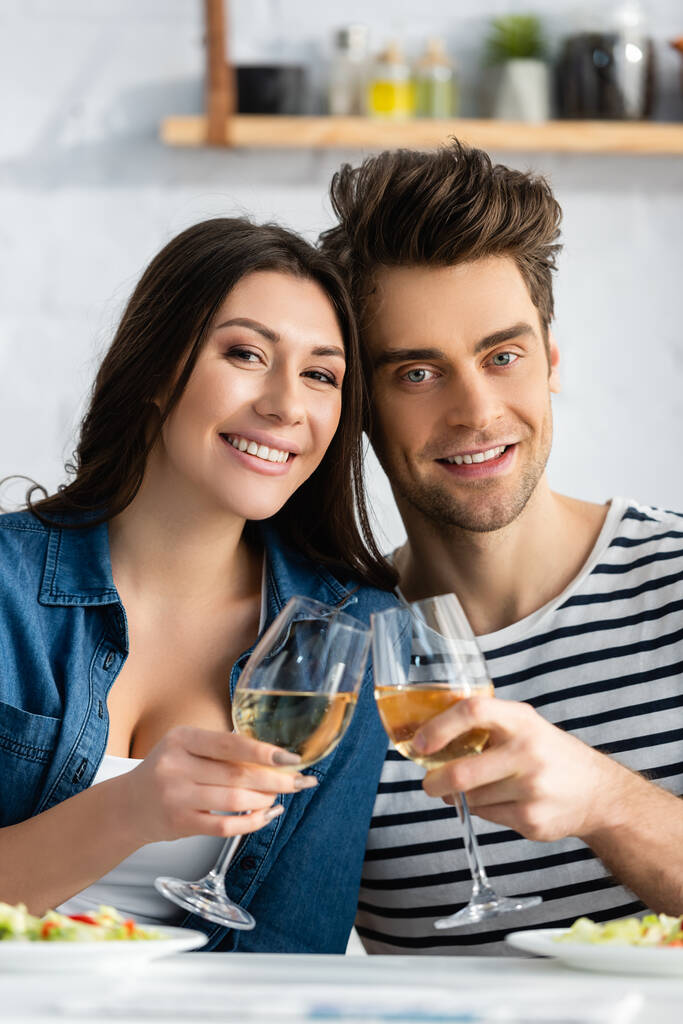 alegre pareja tostando vasos de vino en la cocina  - Foto, imagen