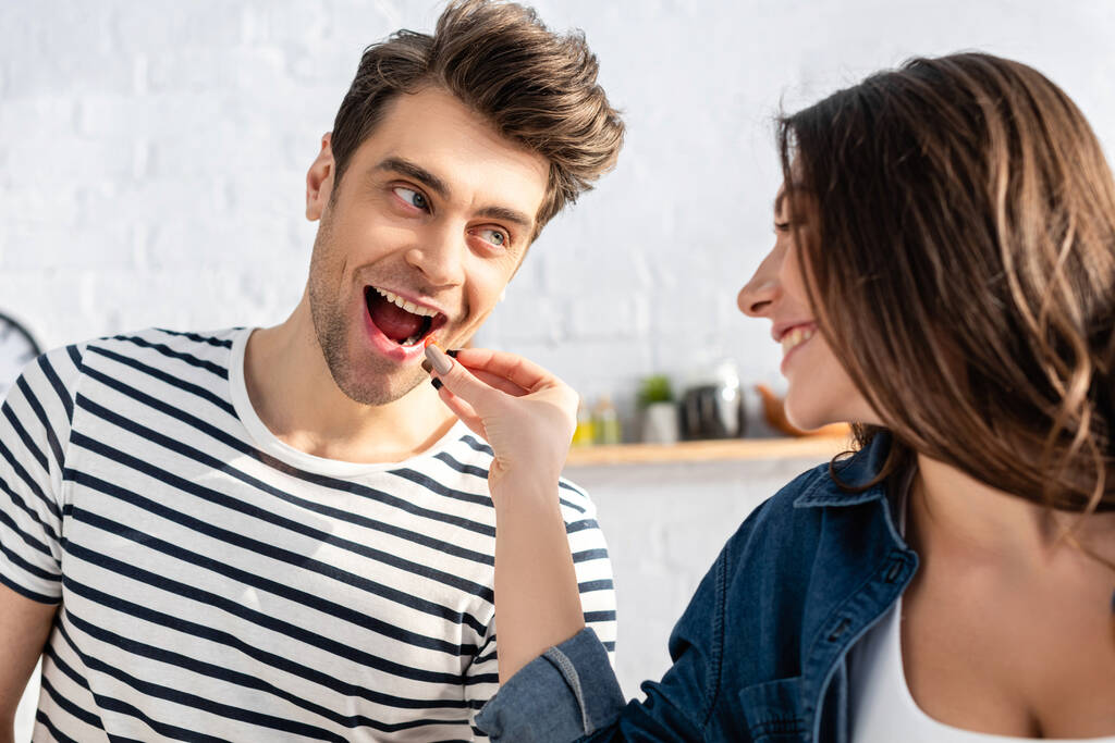 szczęśliwa kobieta karmienie mężczyzna z pomidorem wiśniowym - Zdjęcie, obraz