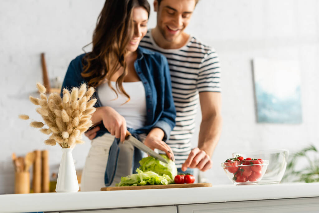 catkins near joyful couple preparing salad in kitchen on blurred background - Photo, Image