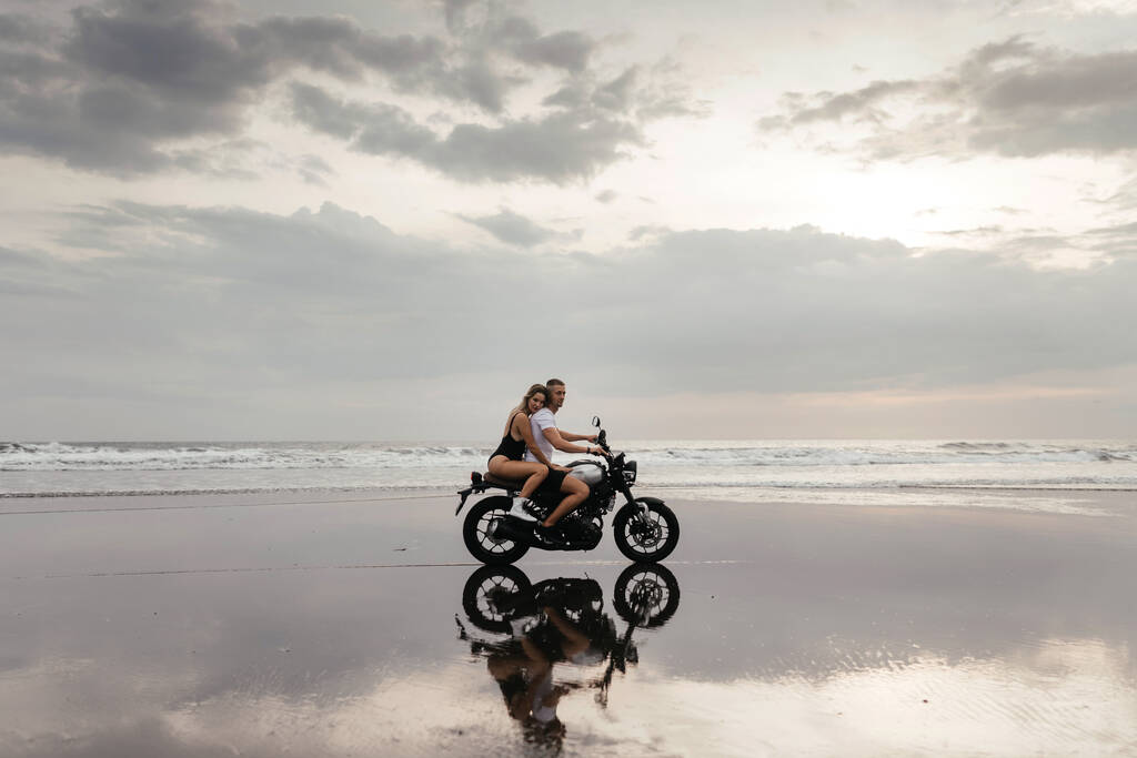 Giovane coppia guida moto sulla spiaggia - Foto, immagini