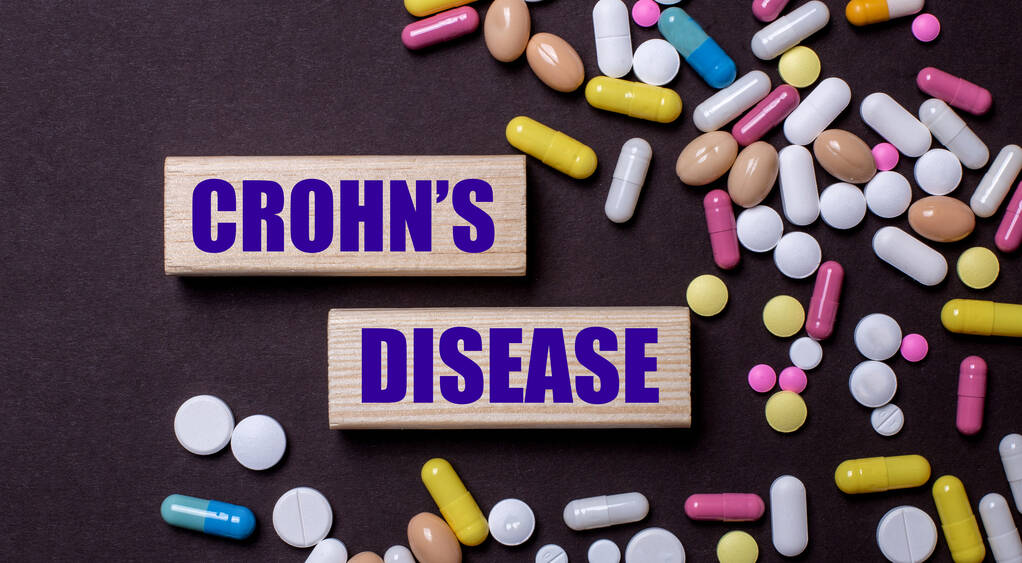 CROHNS DISEASE est écrit sur des blocs de bois près de pilules multicolores. Concept médical - Photo, image