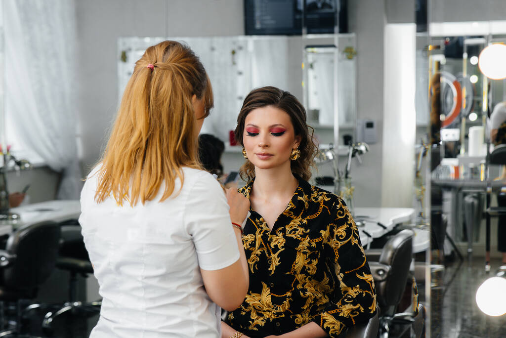 V krásném, moderním salonu krásy, profesionální make-up stylista dělá make-up pro mladou dívku. Krása a móda - Fotografie, Obrázek